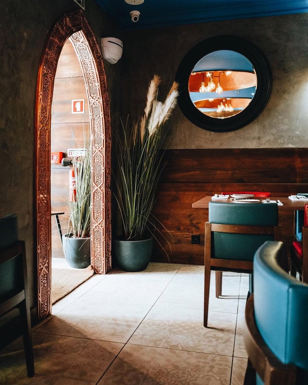 Sala de restaurante remodelada pela Forma Reta — porta em arco marroquino, mobiliário em madeira e iluminação integrada.