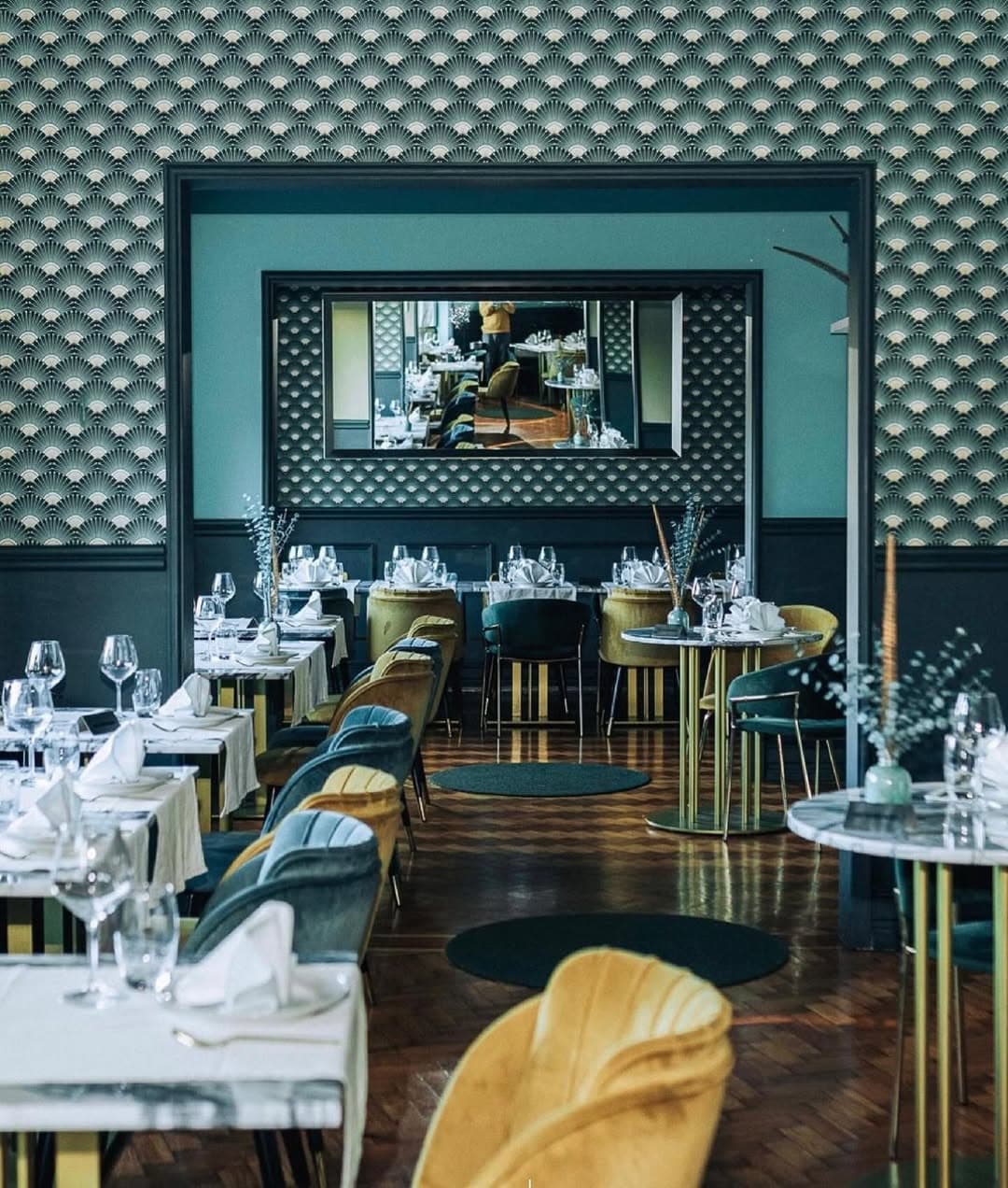 Sala de restaurante em estilo art-déco remodelada pela Forma Reta, com papel de parede verde e mobiliário em veludo.