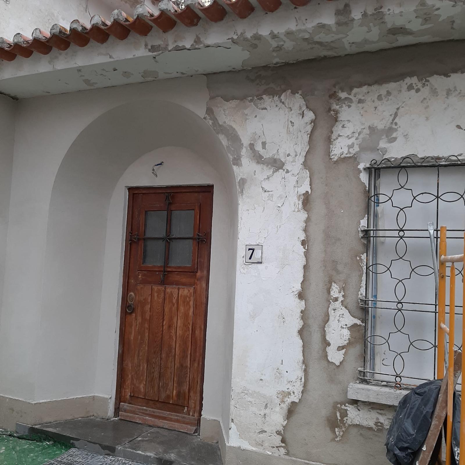 Estado inicial — pátio interior com paredes a descascar, telha solta e jardins esquecidos.