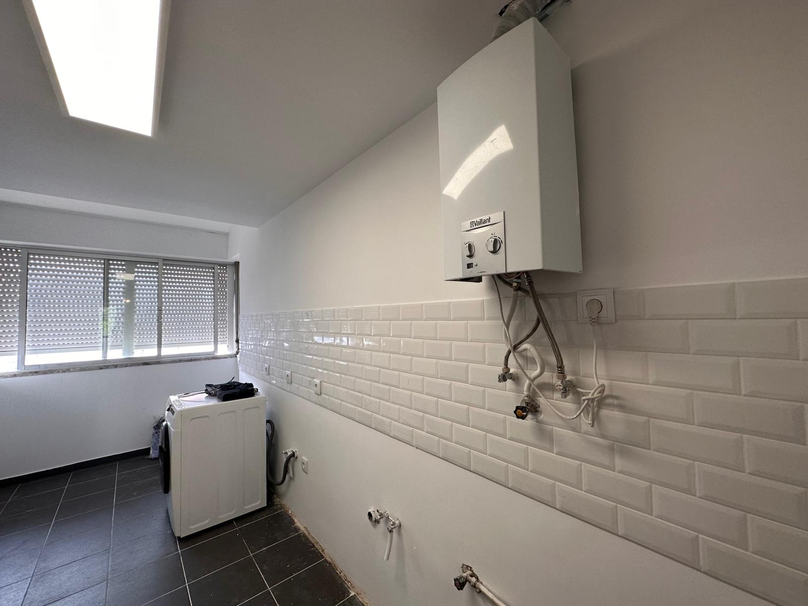 Lavandaria renovada com azulejo metro branco, esquentador Vaillant e instalações novas.